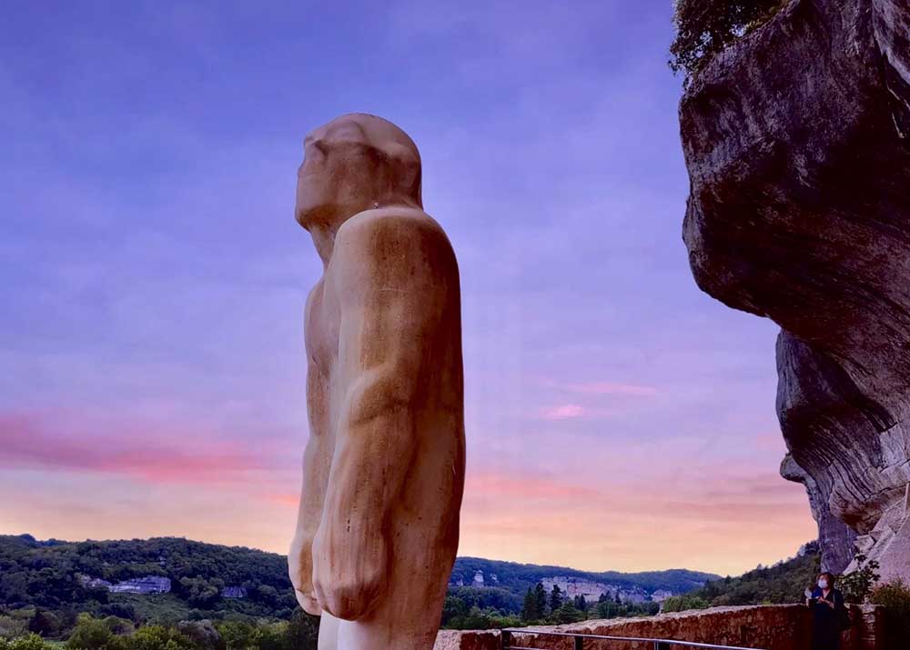 Vor einer Felswand steht ein Mensch aus Stein - der Neandertaler von Les Eyzies. Bild: Netzfund